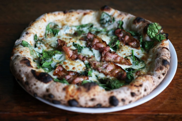 Nomad's wood-fired Guanciale Pizza topped with spinach, mozzarella, fig jam (!), guanciale, Parmigiano Reggiano and garlic. 