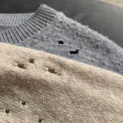 Two cashmere sweaters with holes caused by moth larvae on the shoulders