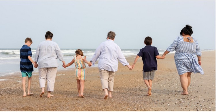 The Watson-Todd family walks together along the beach during a professional photoshoot. CREDIT: Ryan Diegelmann, Coastal Shots Photography