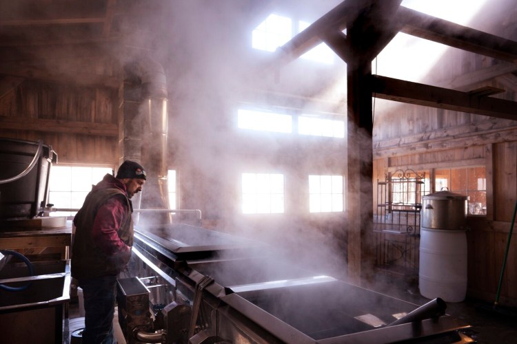 Keith Harris checks on maple sap boiling in an evaporator in a sugarhouse at Harris Farm in Dayton, in 2021.
