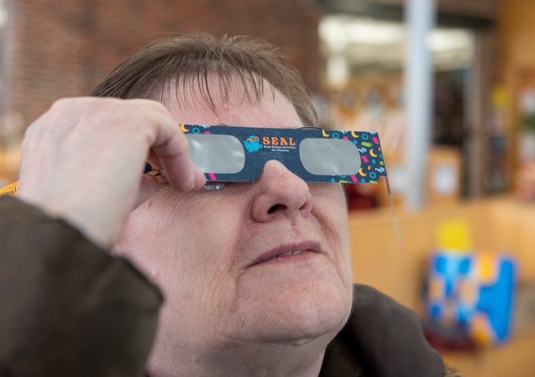 Mary Bielawski of Lewiston tries on eclipse glasses March 27 at the Lewiston Public Library. People all over Maine are getting ready for the next eclipse, April 8. 