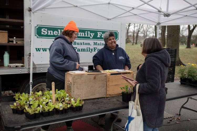 Cindi Stevenson, right, and Carolyn Snell chat with a customer at the Snell Family Farm stand on the first day of the Portland Farmers’ Market in April last year. 